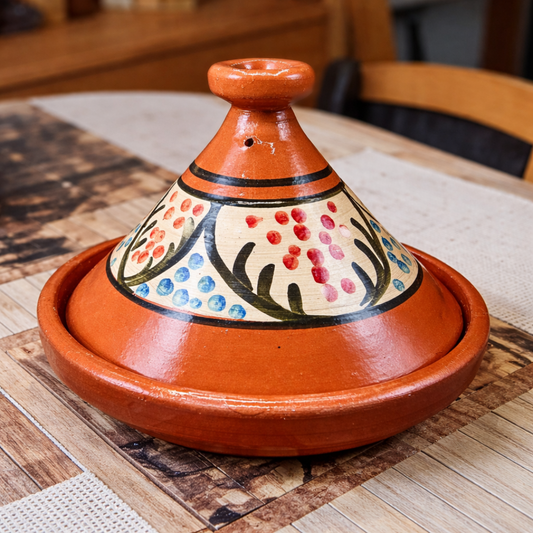 moroccan terracotta tagine with floral patterns on a wooden table for sale.